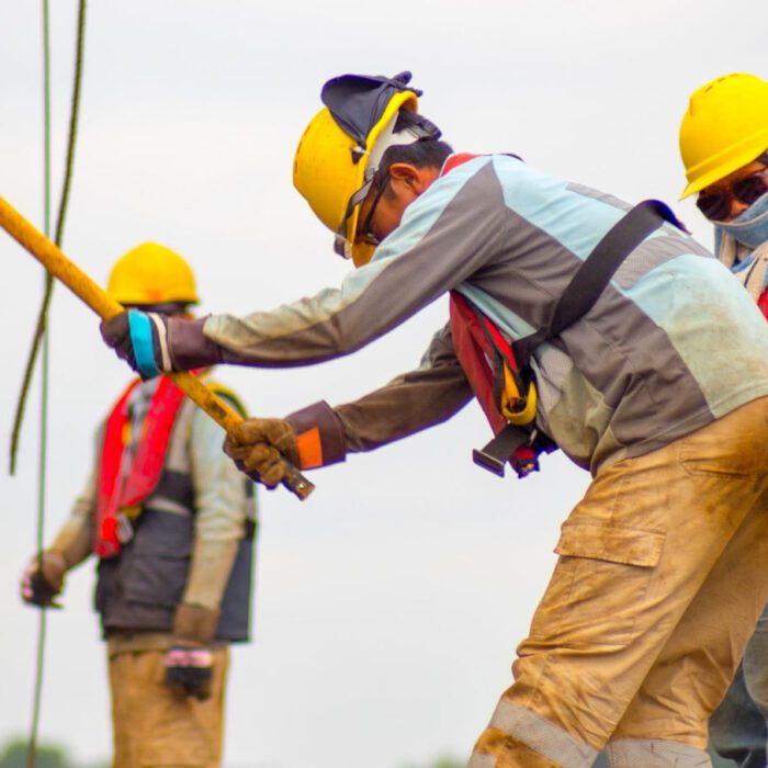 Construction workers in hard hats doing heavy manual work on a job site