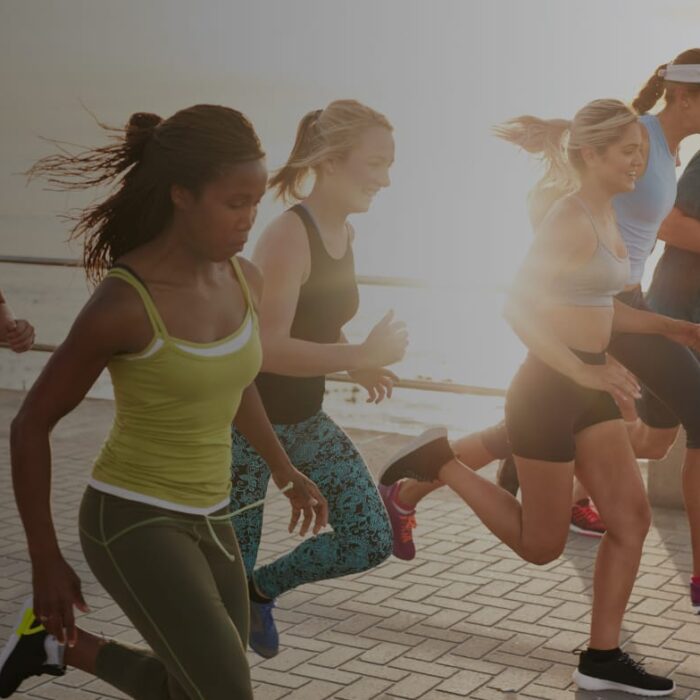 Group of runners training along a waterfront path, the kind of mileage build where shin splints treatment often starts