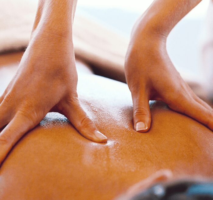 Massage therapist working with both hands along a patient's back