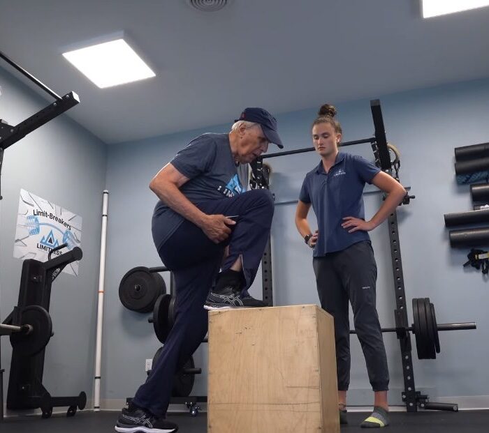 Older man doing a step-up with a physical therapist at Limitless, a milestone on the knee replacement recovery timeline
