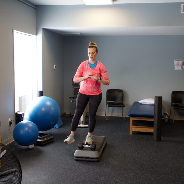 Patient standing on a step platform in a Limitless clinic, the setup used for heel raises in Achilles tendonitis exercises