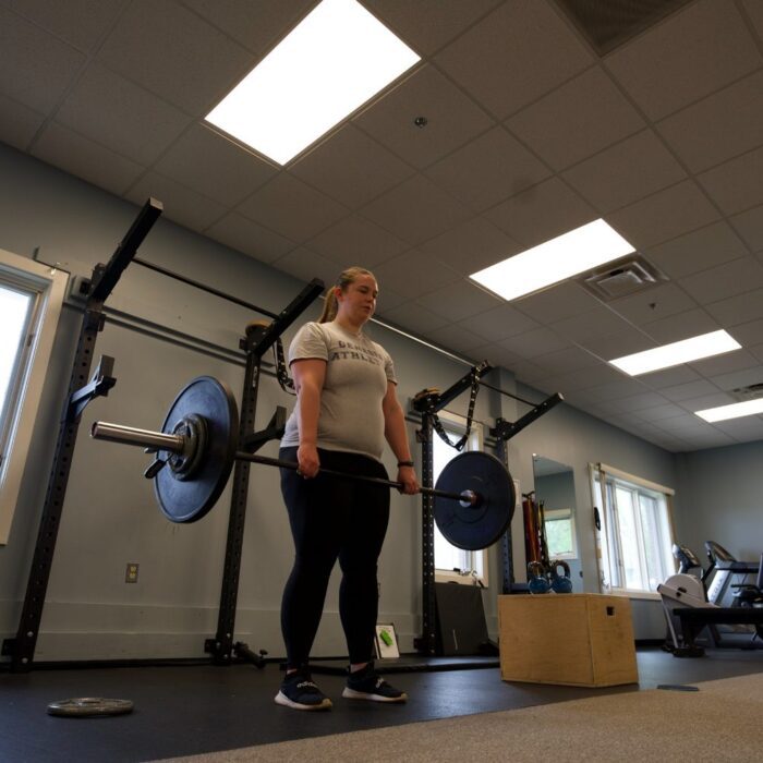 Patient lifting a barbell during late-stage strength work at a Limitless clinic, part of meniscus tear recovery time