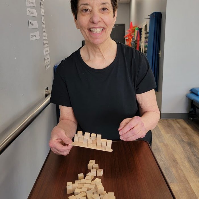 Patient smiling during a fine motor hand dexterity task with wooden blocks